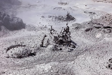 Bubbling mud erupts in a dark geothermal environment, The mud volcanoes and fumaroles on the