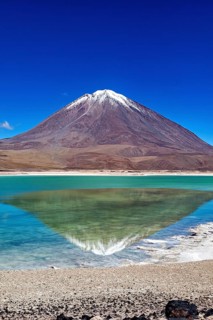 Striking volcano with a turquoise lake whose clear surface reflects the majestic mountain, The