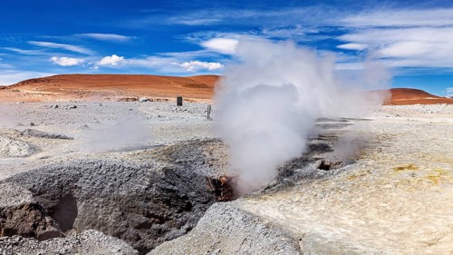 Steam rises from geysers in a rocky desert landscape, sweeping views into the distance, The mud