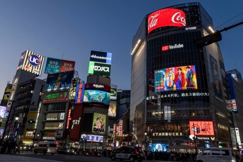 Cars in traffic at Shibuya Crossing, world-famous intersection in the Shibuya district, behind it