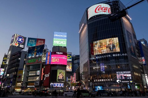 Cars in traffic at Shibuya Crossing, world-famous intersection in the Shibuya district, behind it