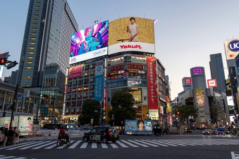 Cars in traffic at Shibuya Crossing, world-famous intersection in the Shibuya district, behind it