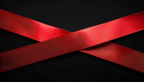 Two vibrant red satin ribbons crossed against a sleek black background, creating a minimalistic and