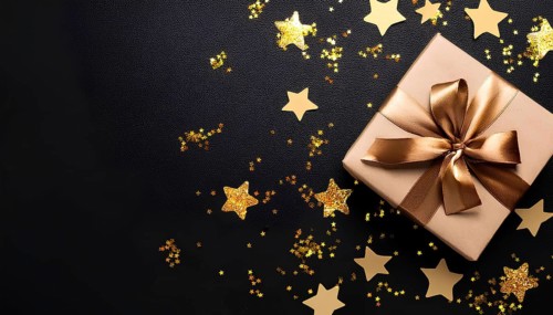 A gold-wrapped gift box with a satin ribbon placed on a black background, surrounded by glittering