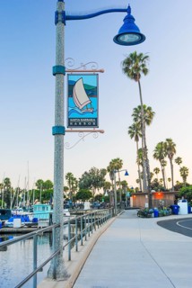 A serene view of Santa Barbara Harbor at dusk, featuring a decorative street lamp with a banner, a