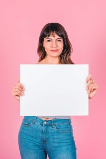 Smiling woman holding a blank sign with copy space for breast cancer awareness