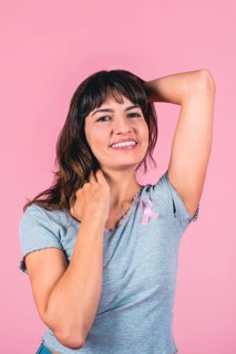 Happy young woman supporting breast cancer awareness with pink ribbon