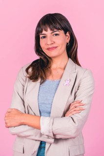 Positive woman with hands behind head and pink ribbon symbolizing breast cancer awareness