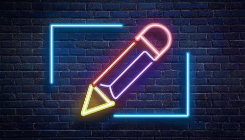 A neon sign in the shape of a pencil is illuminated against a dark brick wall background. The