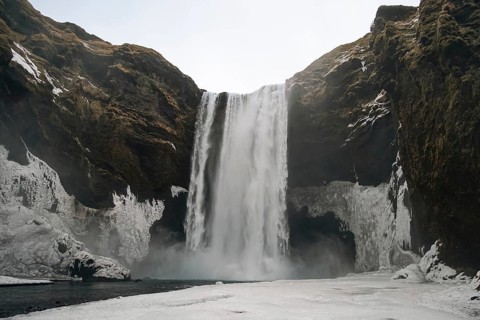 The mighty Skogafoss waterfall in winter. Roaring masses of water meet ice and rock. Skogar,