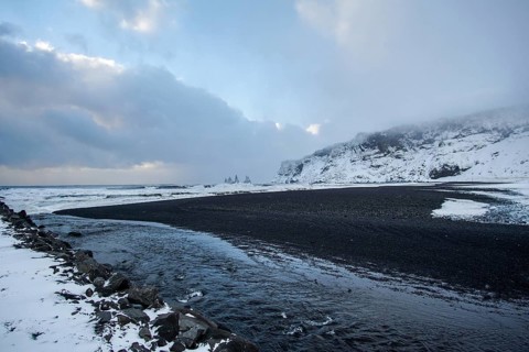 A black beach cuts through white stilts. A coastline like a painting. Renisfjara, Iceland