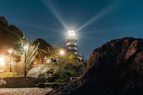 The Sile lighthouse at night. Radiant light over rocks and pine trees. Sile, Istanbul, Turkey