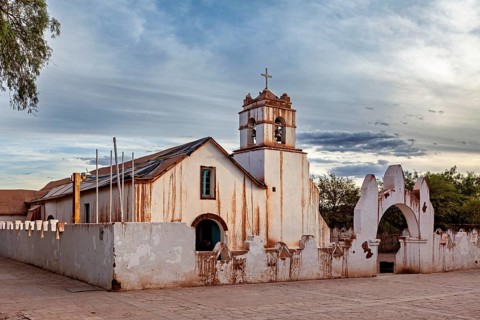 Rustic church under a cloudy sky, striking cross and historic architecture, The church of San Pedro
