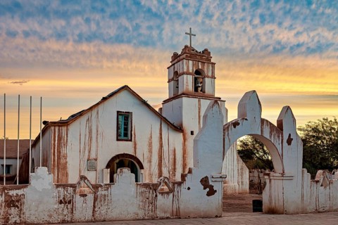Church at dusk with warm colours and a striking church cross in the foreground, The church of San