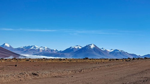 Vast dry desert landscape with snow-capped mountains and clear blue sky, The landscape at San Pedro