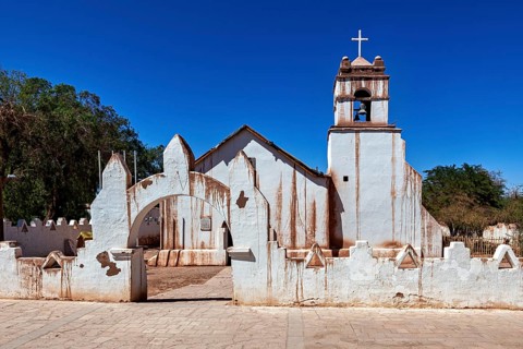 Rustic church with a striking cross under a bright blue sky and clear lines, The church of San