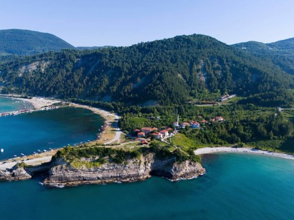 Panoramic view of cliffs and bays with green landscape and calm sea under blue sky, aerial view,