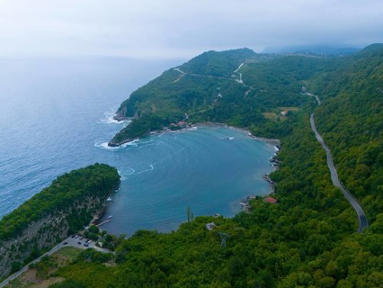 Aerial view of a quiet coastline with wooded mountains and a winding road, aerial view, Gideros