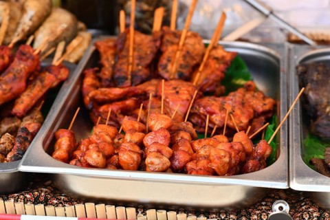 Grilled red marinated Thai meat skewers at street food market
