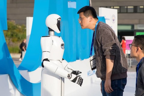 A person looks at a robot at the IFA consumer electronics exhibition on the exhibition grounds,