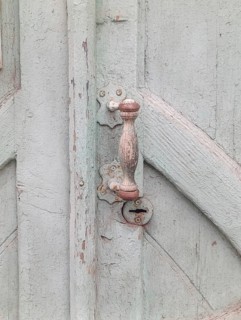 Fragment of a gray old wooden door with a handle