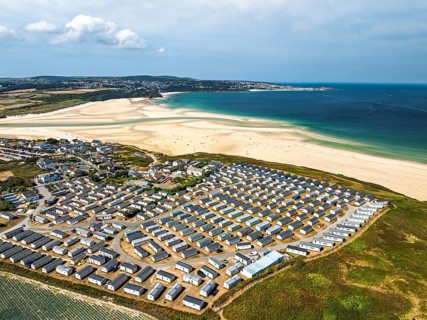 Holiday homes over Hayle Beach and Hayle Estuary from drone, St Ives Bay, Cornwall, England, United
