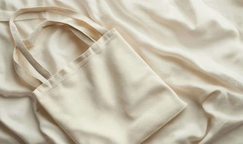 A cream canvas bag on a draped fabric with soft lighting emphasizing texture. AI generated