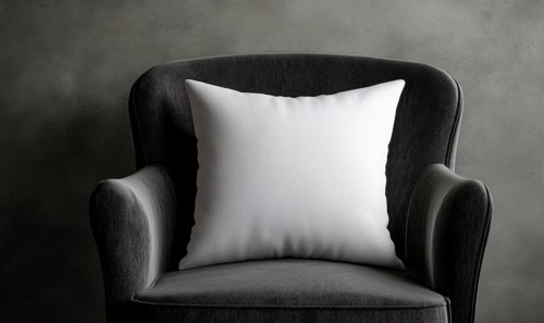 A white pillow sits on a black chair. The chair is made of wood and has a natural texture. The