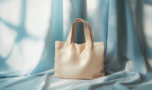 A tan purse is sitting on a blue cloth. The purse is made of leather and has a pattern on it. The