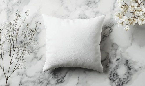 A soft white pillow on a marble surface with delicate flowers under gentle lighting. AI generated