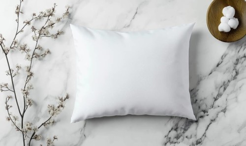 A white pillow sits on a marble countertop. The pillow is unmade and has a floral pattern on it.