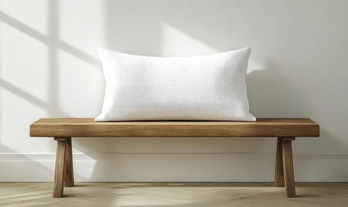 A minimalist wooden bench with a white pillow lit by warm natural light. AI generated