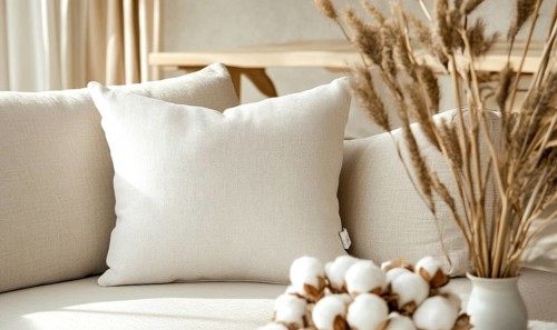A cozy arrangement of pillows and cotton stems in a softly lit room creates a warm atmosphere. AI