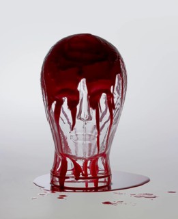 Generic human dummy head made of glass, overwhelmed with red fluid in light grey back