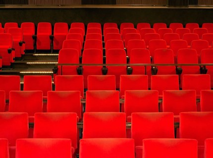 Indoor scenery showing a movie theater with red seats in warm ambiance