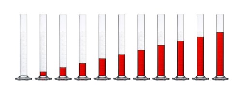 Row of measuring cylinders made of glass, gradually filled with translucent red fluid in front of