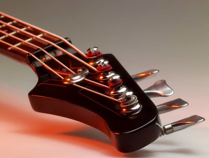 Detail of a bass guitar with red light in grey back