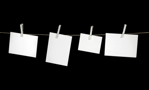Clothesline with some white labels fixed with clothes pins in black back