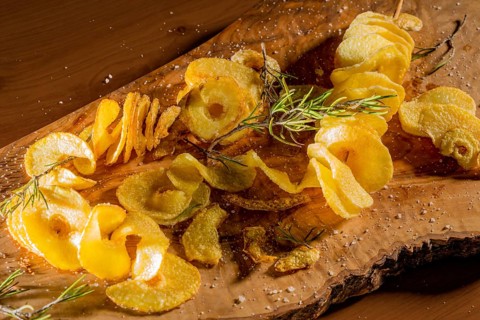 Some deep-fried spiral-sliced potatoes with some thyme on wooden board