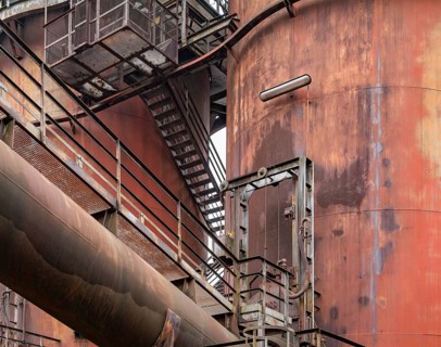 Weathered rundown industrial scenery with old corroded steel girders, stairs and metal tubes