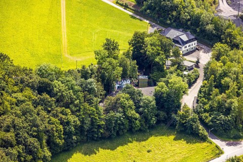 Aerial view, open-air stage covered by trees and adjacent buildings with towers, on the right
