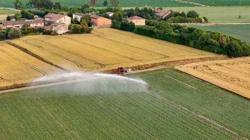 Modern Agricultural Irrigation System Sprays Water Over Green Soybean Fields Under a Bright