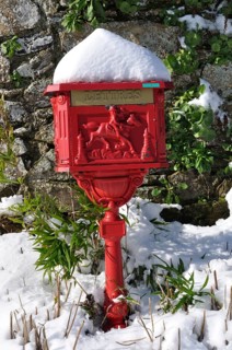 Vintage red mailbox under the snow, Ornate red mailbox covered in snow against a stone wall with