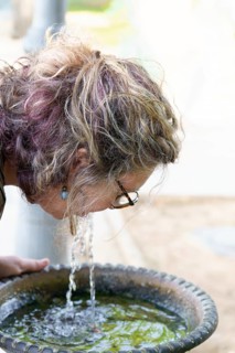 Woman refreshing herself by drinking water directly from a park fountain