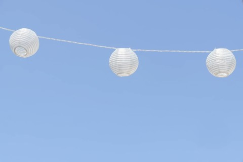 White paper lanterns decorating an outdoor space, adding a festive touch against a clear blue sky