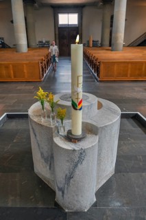 The Roman Catholic parish church of St Martin, interior with baptismal font, candle and floral