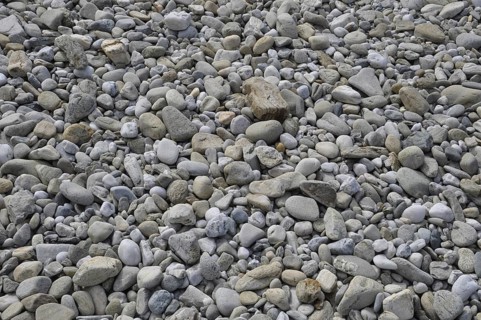 Pebbles background on a beach, A close-up view of a surface covered with various shapes and sizes
