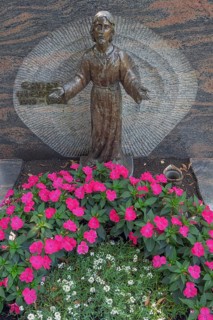 Gravesite with Christ figure and floral decorations, noble lily (Impatiens New Guinea) Catholic