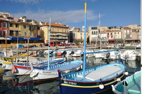 Cassis, the port, A vibrant harbor scene with colorful boats floating in calm water, lined by