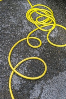 Twisted yellow water hose on asphalt, Allgäu, Bavaria, Germany